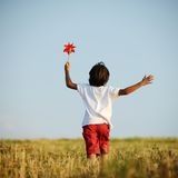 Child walking and running on field holding red spinning flower
